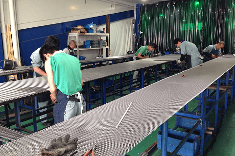 工場でメッシュベルトを製造する社員たち